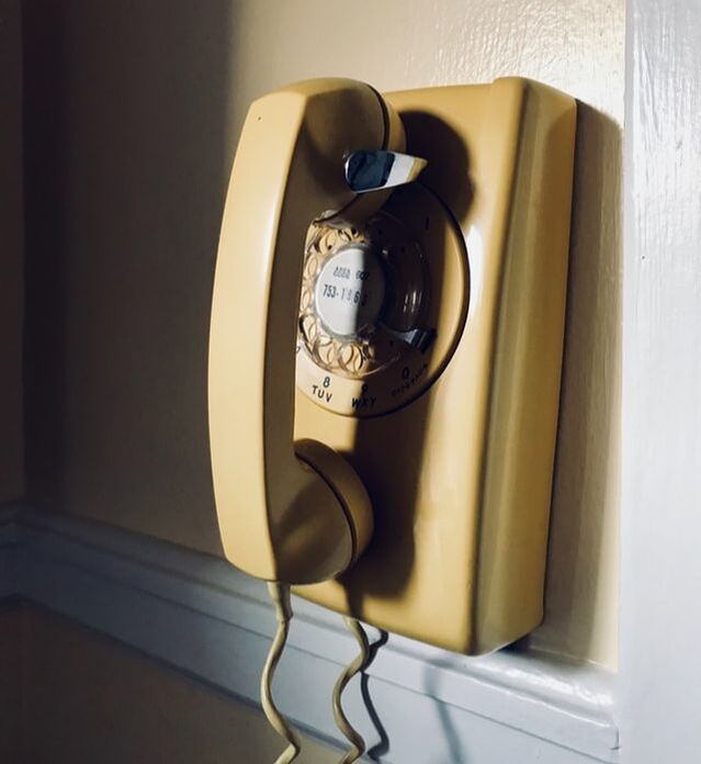 old yellow rotary phone on wall